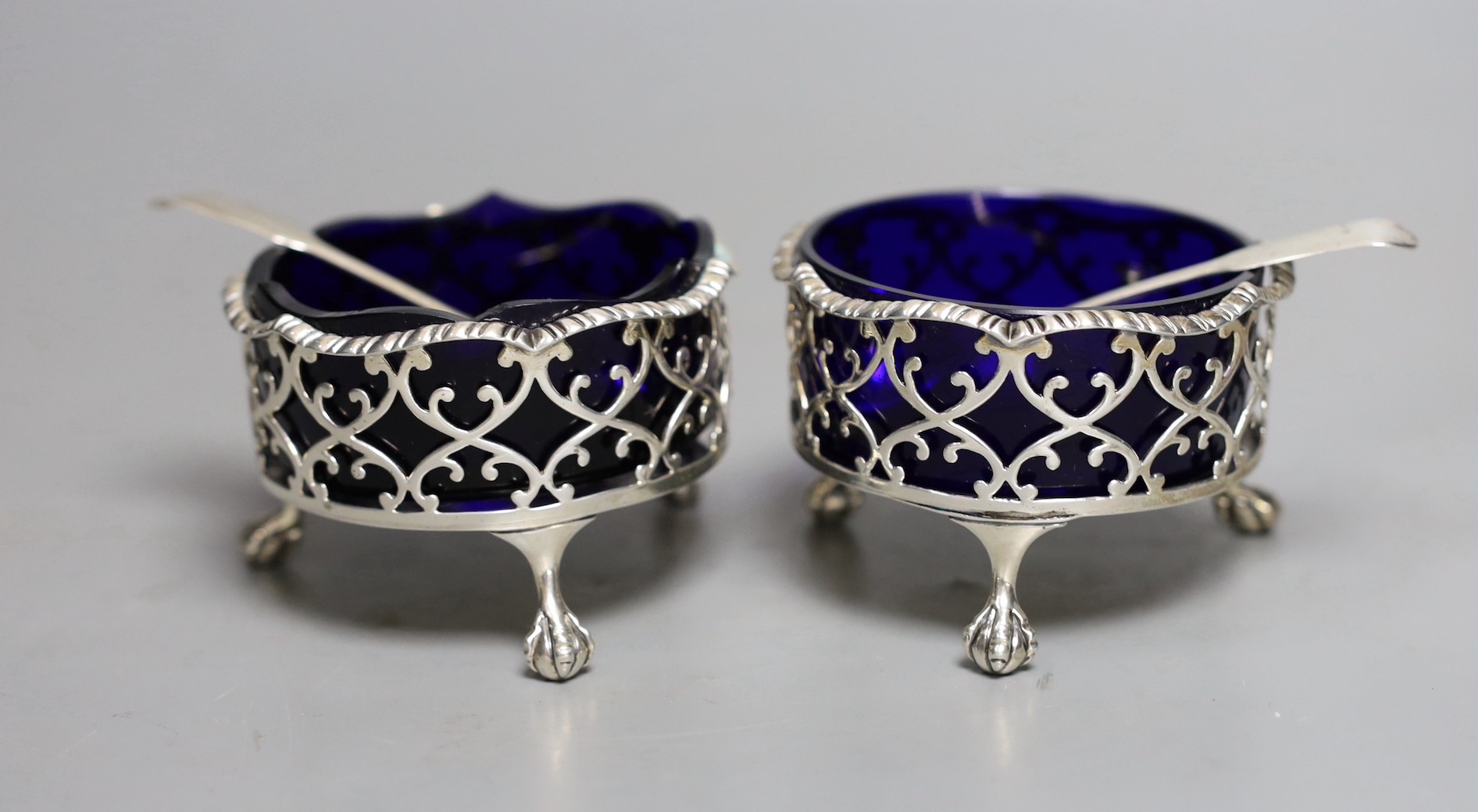 A pair of George III pierced silver circular salts, London, 1764, 79mm, with two associated spoons.